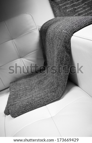 it is a gray blanket draped over a leather couch