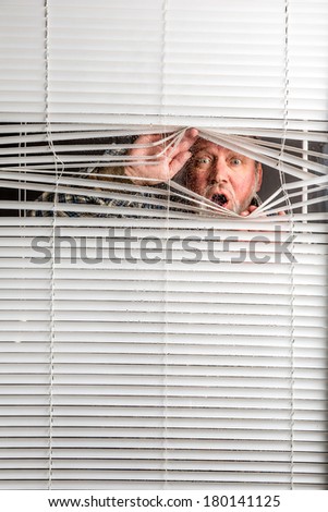 Agoraphobia. A man looking through a rain spotted window blinds with facial expressions.