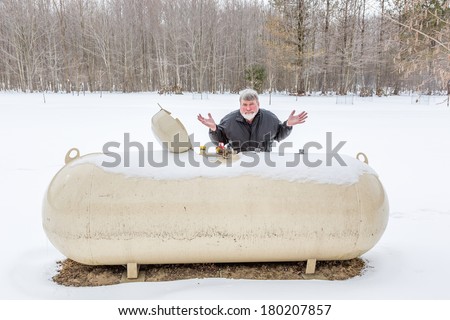 A man with facial expressions looking at a bulk propane storage tank.
