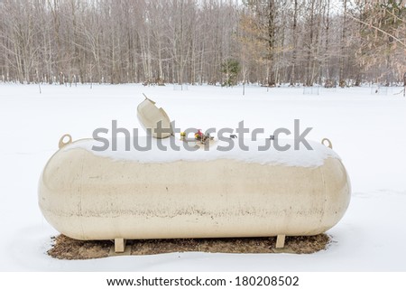 a bulk storage propane tank with lid open in a snow covered landscape