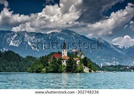 Cloudy day on the lake Bled, view on the island with the Assumption of Mary Church and Julian Alps, Slovenia, Europe