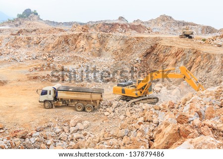 wide angle shot excavator loading crushed rock on  dumper truck at dolomite mines site