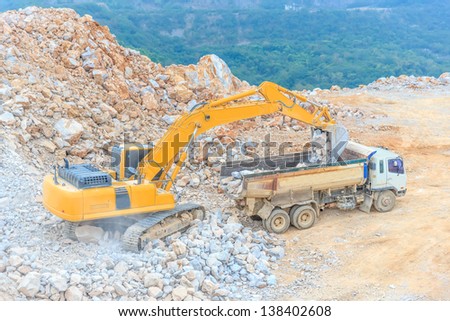 excavator loading dumper truck with crushed rock at dolomite mines site