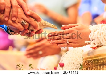 hands pouring blessing water into bride's bands, Thai wedding ceremony