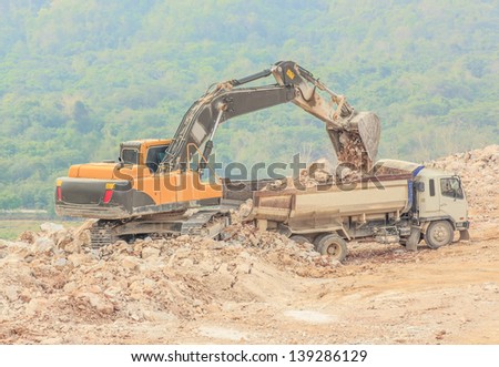 excavator loading dumper truck with sand at dolomite mines site