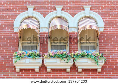 vintage window awnings with curtain decorated with flowerpot on red brick background