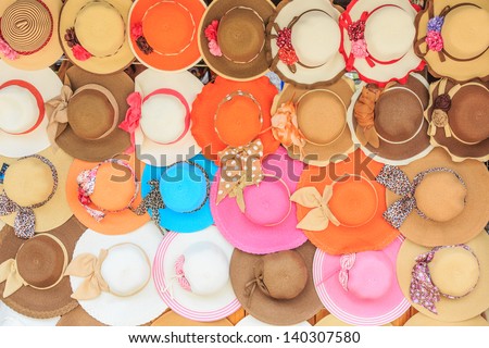 Colorful women hat hanging on the wall of country shop.