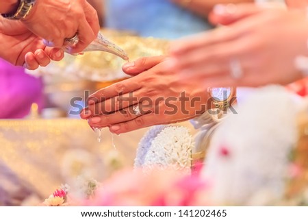 hands pouring blessing water into groom\'s bands, Thai wedding ceremony