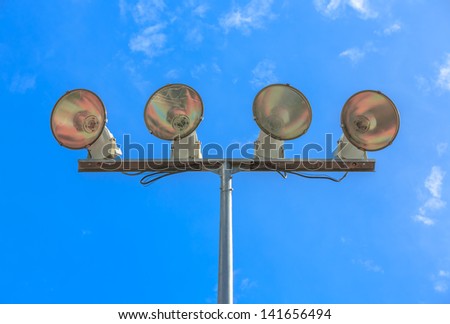 Stadium flood lights at basketball field against blues sky and white cloud