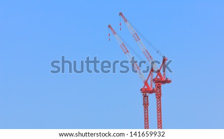 two white and red crane against blue sky