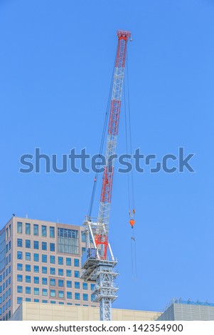 single white and red crane against blue sky