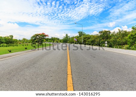 center yellow line of the road against blue sky and white cloud