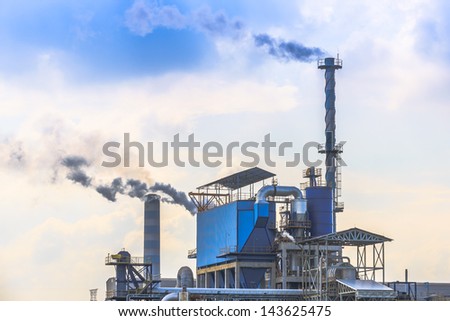 smoking of three chimneys from a factory against a blue sky
