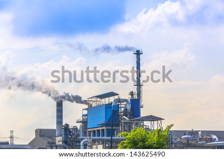 smoking of three chimneys from a factory against a blue sky