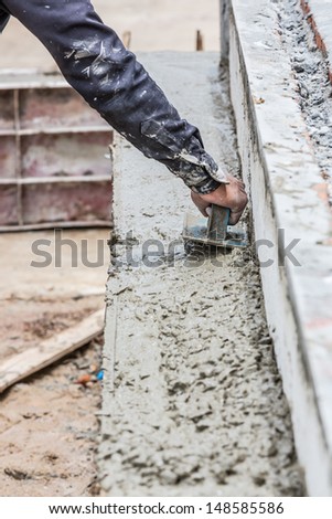 Construction worker spreading wet concrete on the beam casting