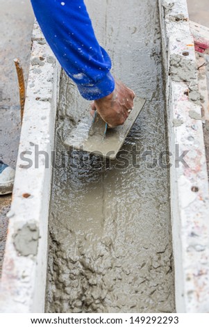 Construction worker spreading wet concrete on the beam casting