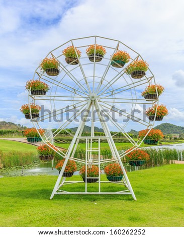 flowerpot in shape of ferris wheel against white cloud and blue sky