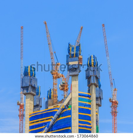 group of building cranes  on top of the building under construction against blue sky