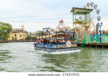 MALACCA, MALAYSIA - DECEMBER 23: Tourists boat and Malacca eye on the banks of Melaka river on Dec 23, 2013 in, Malaysia. Malacca has been listed as a UNESCO World Heritage Site since 7 July 2008.