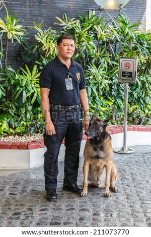 MANILA - FEB 12: Unidentified security guard with dog at Diamond Hotel on 12 Feb, 14 in Manila. It is estimated 3.7 million of security guards including doormen in the Philippines.