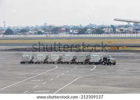 MANILA - FEBRUARY 15:  Worker pulling container pallets at Ninoi International Airport on Feb 15, 14 in Manila, Philippines. It is the airport serving Manila and its surrounding metropolitan area.