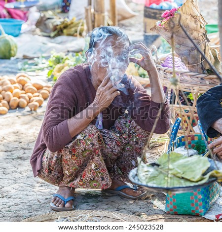 INLE LAKE, MYANMAR - DEC 8: Woman smoke cigarette at 5 Day market on Dec 8, 2014 in Inle. Hand-made goods and food for local use and trading are another source of commerce in Inle.