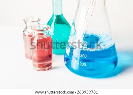 Scientific laboratory glass conical Erlenmeyer flask filled with amber orange chemical liquid with glassware equipment in fog or smoke for a chemistry experiment in a science research lab