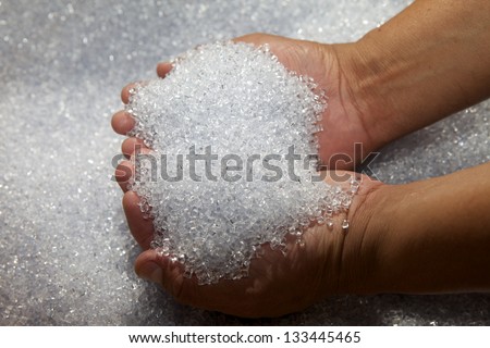 Man\'s hands holding a pile of plastic pellets, white colored