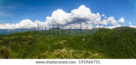 panorama of the countryside with meadows, roads, houses and mountains with blue sky and clouds in Abkhazia