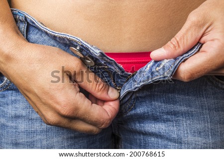 woman unzips his pants on blue jeans, and from under them visible red underwear