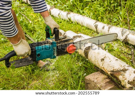 man sawing wood for firewood, using electric chainsaws
