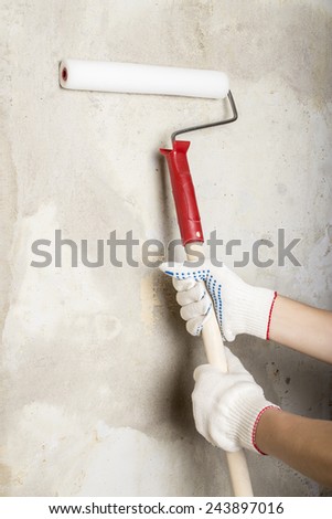 Man paints the wall roller holding in both hands