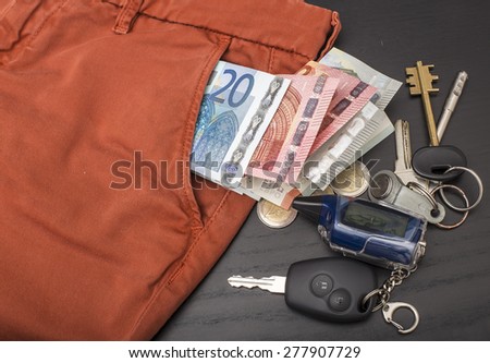 euro money and coins fell out of his trouser pocket on black table on which lie the keys to the house and car