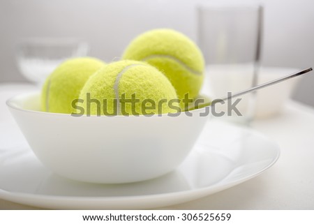 Tennis balls are in a bowl instead of ice cream, symbolizing changes and refusal of desserts and sweet and replacement of sports and healthy lifestyle. White variant.