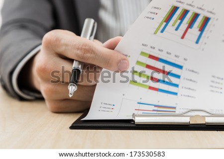 Businessman's hand showing financial report on table