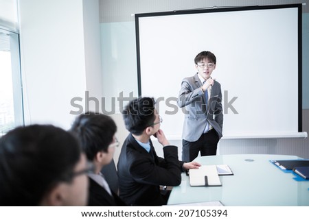 Smiling businessman discussing plans with his colleagues in board meeting.asian