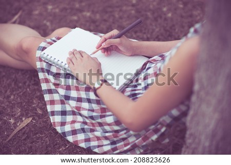 Close-up of a young girl writing into her diary, in the park