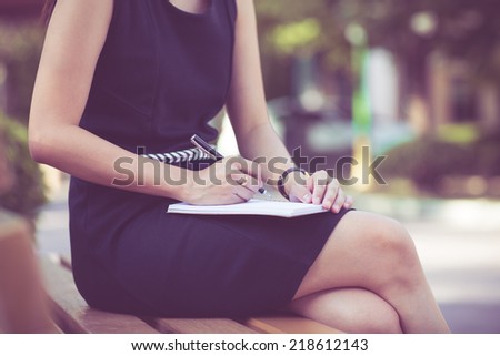 Young business woman planing, writing and reviewing report at city park.