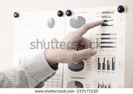 Businessman pointing to flip board with chart in office