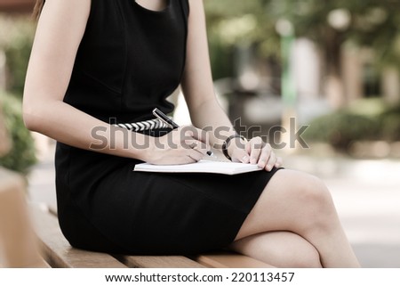 Young business woman planing, writing and reviewing report at city park.
