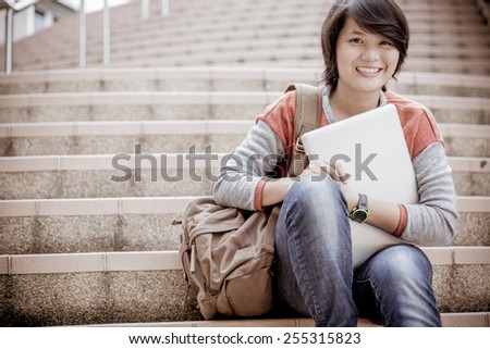 Young woman using laptop on steps outdoors