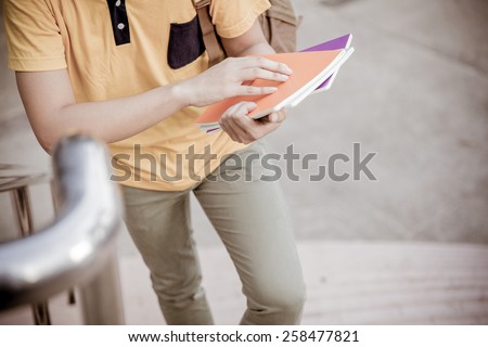 young college student reading book on stairs
