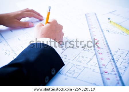 Hands of civil engineer correcting a blueprint