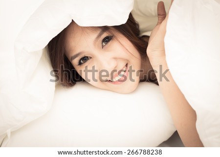Pretty young woman in bed under the white bed sheet