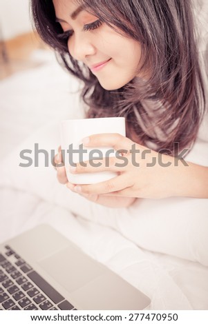 beautiful young woman hold cup of coffee lying think relaxing on the couch
