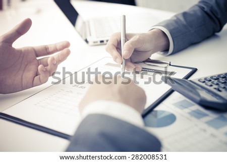 Two businessmen looking at report and having a discussion in office.