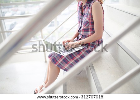 Young professional business woman sitting on the steps of an old stone building using a laptop computer working outdoors