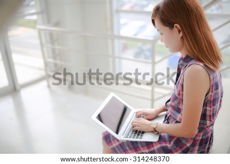 Young professional business woman sitting on the steps of an old stone building using a laptop computer working outdoors