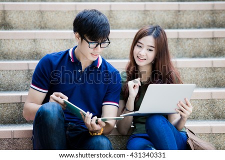 Two students studying with computer notebook outdoors