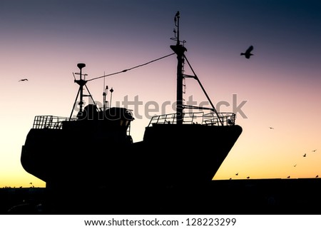 Fishing vessel silhouette at sunset in port, Essaouira, Morocco